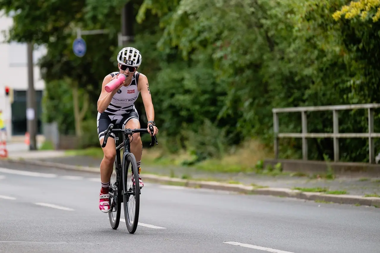 Cyklist på landevej der drikker af en drikkedunk